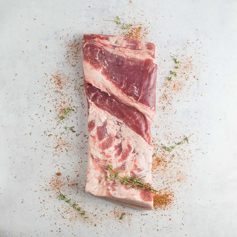Iberico Pork Belly (Panceta) laid on marble with some seasonings, seen from above.