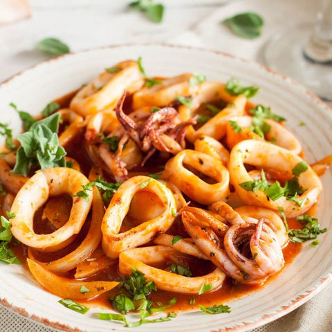 Argentinian Calamari Rings cooked in a round plate with salad, front view.
