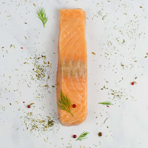 Norwegian Salmon laid out on marble, with some dill leaves and pink peppercorns, seen from above.