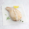 Piece of wild monkfish arranged on a napkin on marble with lemon, seen from above. 