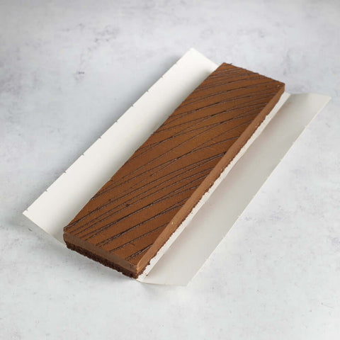 A large Crunchy Chocolate Hazelnut Strip Cake in its cardboard packaging, seen from above. 