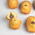 Assorted Chocolatey Hazelnut Filled Madeleines with one cut in half, arranged on marble, seen above. 