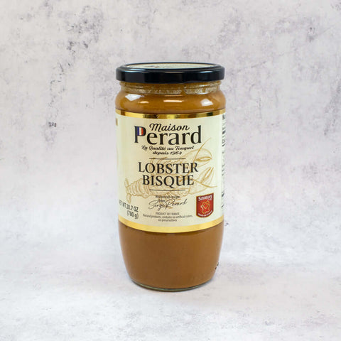 A glass jar of Lobster Soup from Maison Perard placed on marble, seen from the front.