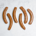 1 pack of 6 Lamb Merguez Sausage set on marble, seen from above.