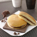 Chocolate and Hazelnut Filled Pancake filling, one cut in half, placed on a napkin, front view.