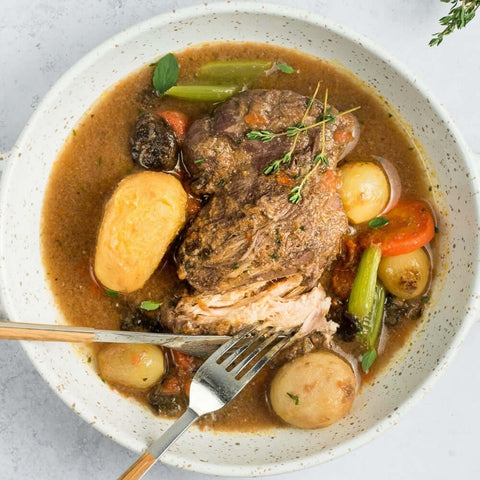 Coq au Vin cooked in a round dish on marble, seen from above.