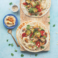 Grilled Potatoes and Zucchini Mix arranged in pita breads on a wooden board, seen from above. 